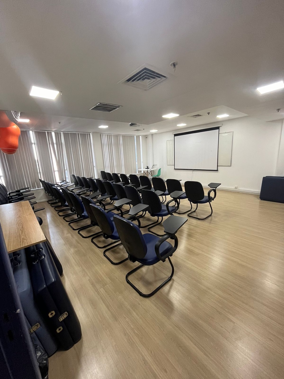 Auditório 1 com cadeiras com prancheta, tela de projeção e quadro branco