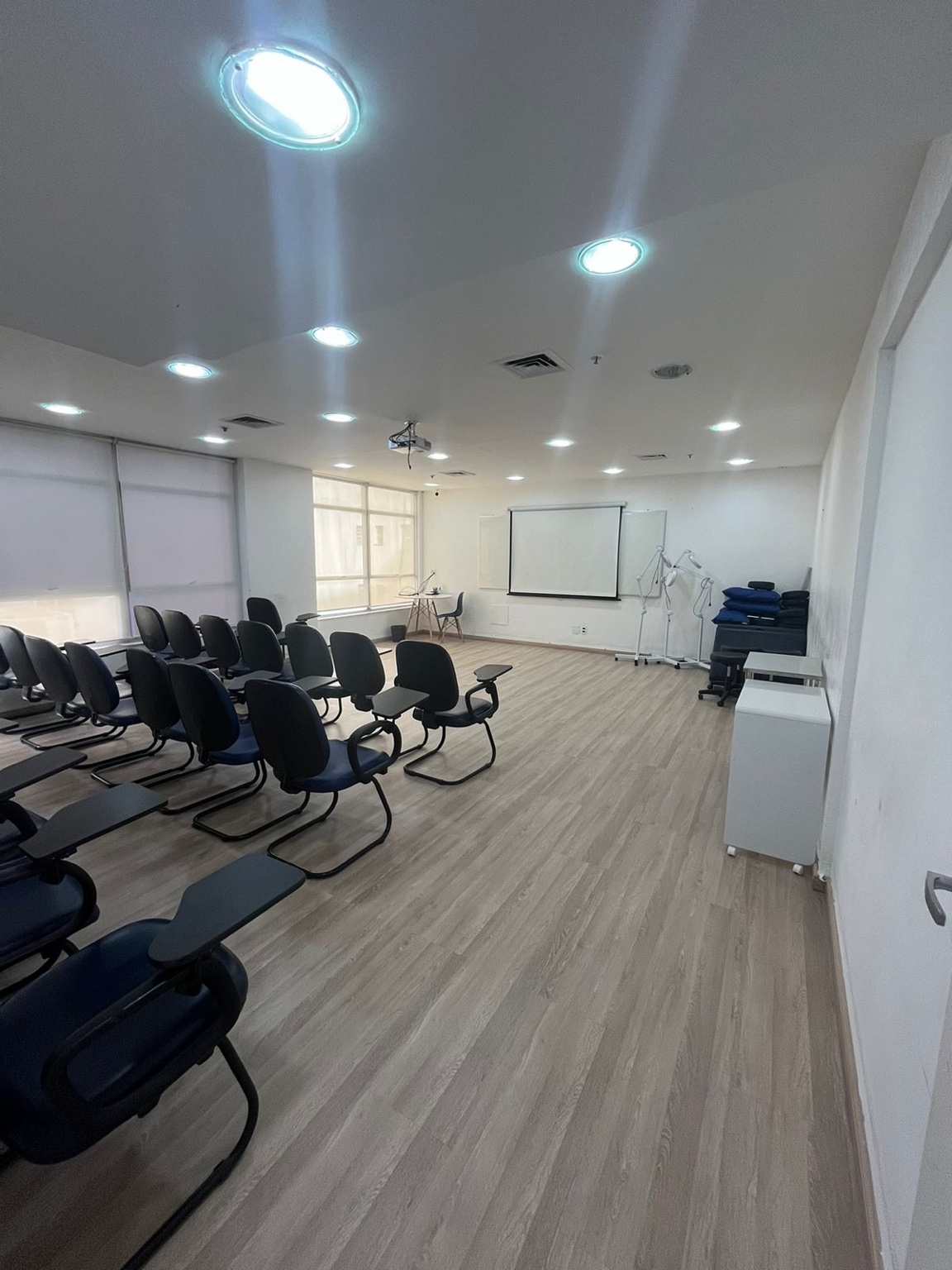 Auditório 4 da InterFISIO com cadeiras com prancheta, tela de projeção e área frontal livre